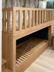 ciemno-zielone panele tapicerowane w zabudowie łóżka dziecięcego z antresolą