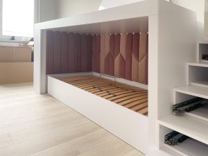 tapicerowane panele w zabudowie łóżka dziecięcego w odcieniach jasnego i ciemnego różu naprzemian