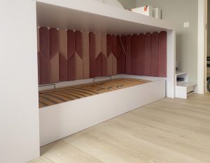 tapicerowane panele w zabudowie łóżka dziecięcego w odcieniach jasnego i ciemnego różu naprzemian