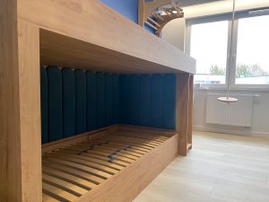 granatowe panele tapicerowane w zabudowie łóżka dziecięcego