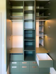 ciemno - zielona szafa w pokoju dziecięcym z wieloma półkami i szufladami